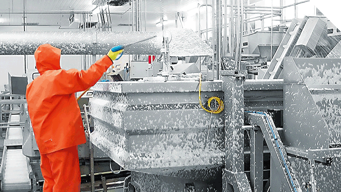 Industriereinigung mit Schaumverfahren – Reinigungskraft beim Säubern einer Produktionsanlage mit Schutzkleidung